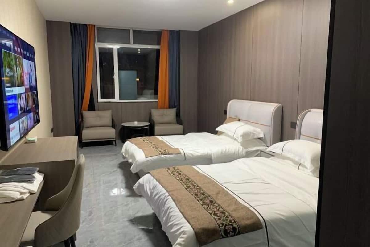 Een hotelkamer met twee bedden, een bureau, een stoel, een klein tafeltje en een televisie.