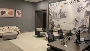 A modern office space with a sofa, a desk with a computer, and a large painting on the wall. - Yurong Shanzhuang Hotel (Nanjing)