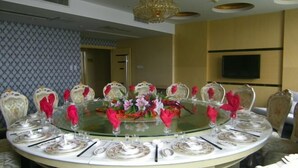 A round dining table set for a formal meal with floral centerpieces, surrounded by ornate chairs. - Yurong Shanzhuang Hotel (Nanjing)