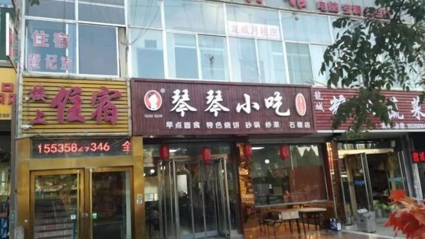 A building with multiple signs, including one for a restaurant named "Qin Gen" and another for a hotel. - Longcheng Hotel (Shilou)