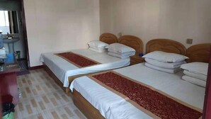 A hotel room with two single beds, a small desk, a mirror, and a sink. - Longcheng Hotel (Shilou)