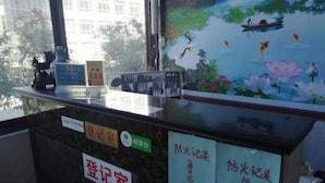 A reception desk with a glass partition, a framed painting of a pond with birds and flowers, and signs indicating a registration room and a fire safety record room. - Longcheng Hotel (Shilou)
