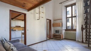 A spacious living area with a sofa, a television, and a kitchen in the background. - Santa Maria Novella Bright and Modern Apartment (Florence)