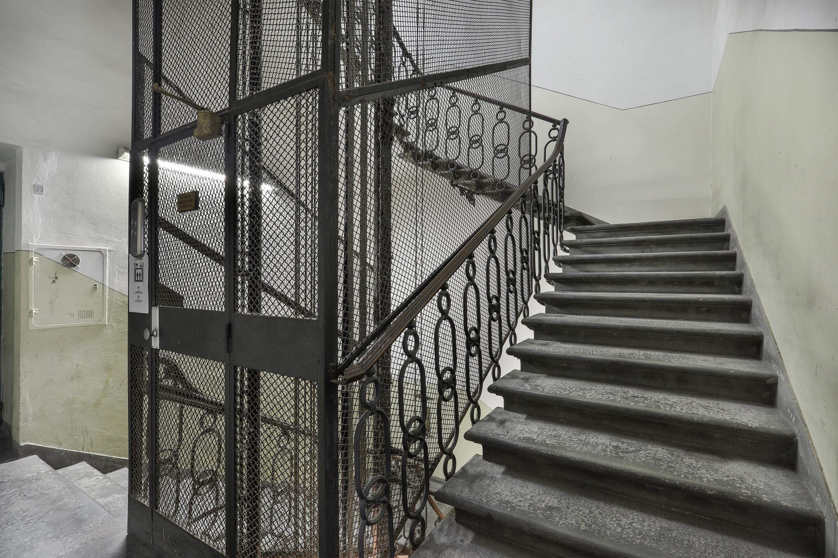 Un escalier avec des rampes en métal et une porte grillagée.