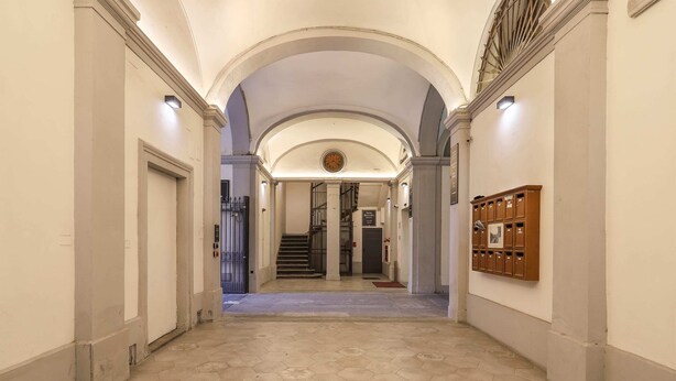 A hallway with hexagonal patterned flooring, arched ceilings, and a row of wooden lockers on the right. - Santa Maria Novella Bright and Modern Apartment (Florence)