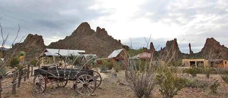 A rustic setting with a vintage carriage, rocky terrain, and sparse vegetation.