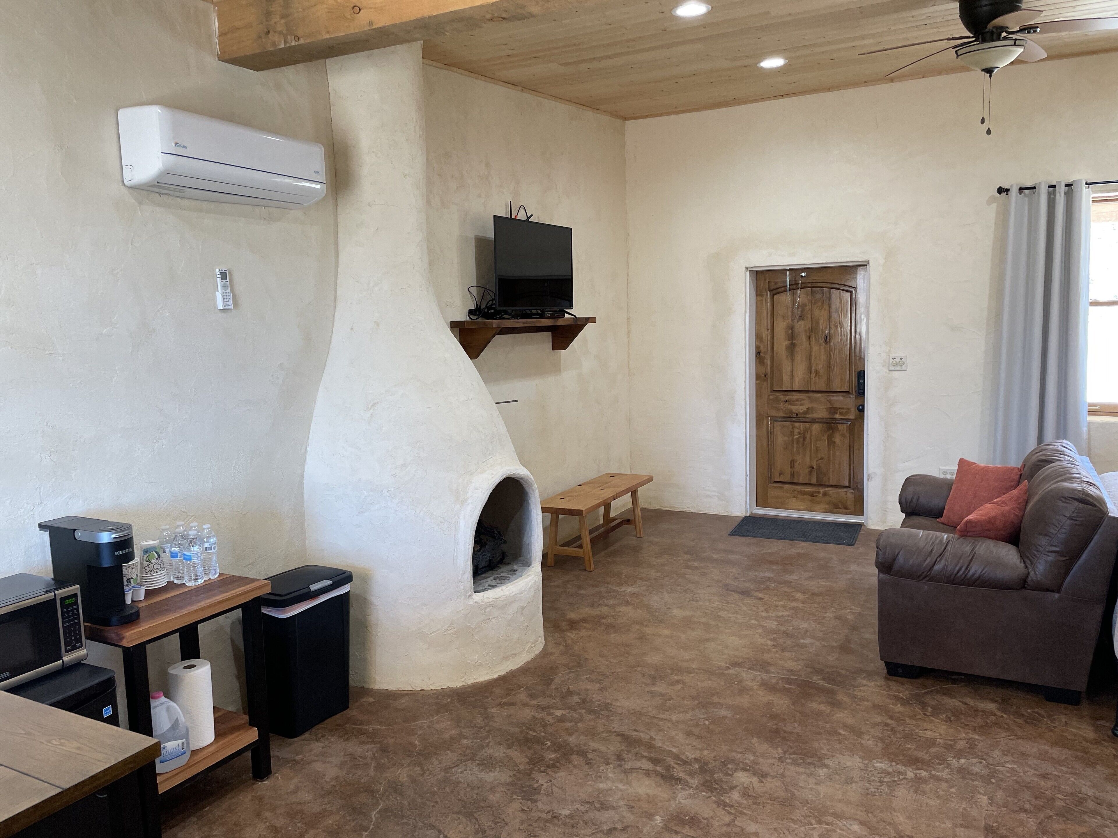 A living room with a stone oven, a television, a sofa, and a wooden door.