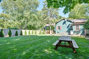 Ein Garten mit einem Holztisch, einem Haus mit grüner Fassade und einem Holzzaun.