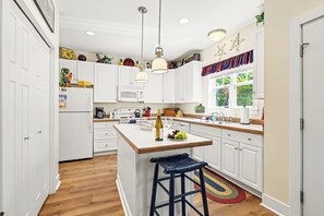 A modern kitchen with white cabinets, a wooden island, and a bar stool.
