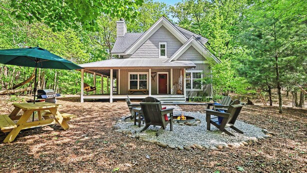 Una casa con porche, mesa de picnic y mobiliario exterior.