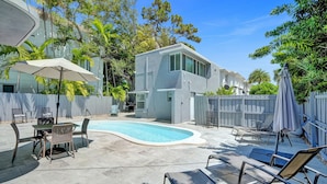 Une maison moderne dotée d’une piscine, de mobilier d’extérieur et d’une végétation luxuriante.