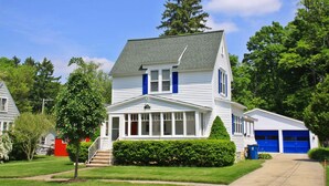 A two-story house with a front porch, a garage, and a well-maintained lawn. - Malabar: Downtown Saugatuck Cottage, Fire Pit, Pet Friendly, Sun Room, Porch (Saugatuck)