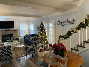 Una sala de estar con chimenea, un árbol de Navidad y una escalera adornada con guirnaldas.