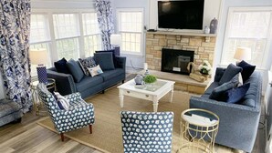 Una sala de estar con sofá, sillones, una mesa de centro y chimenea.
