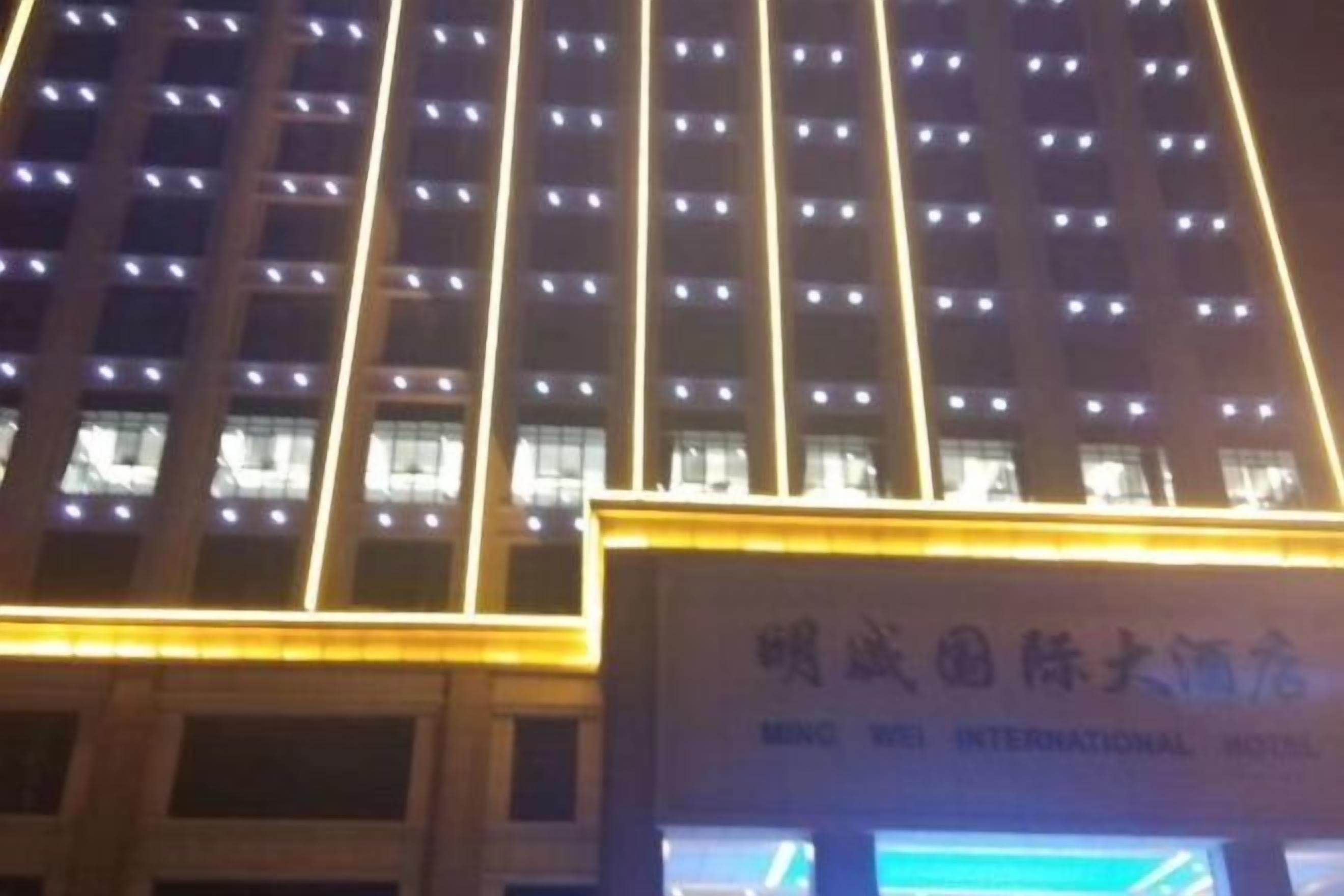 Fachada de un edificio con ventanas iluminadas y un cartel que indica que es el Hotel Internacional Ming Xi.