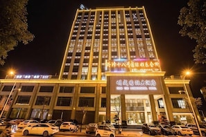 Un hôtel à plusieurs étages, doté d’une enseigne lumineuse, d’un parking et d’une entrée bien éclairée.