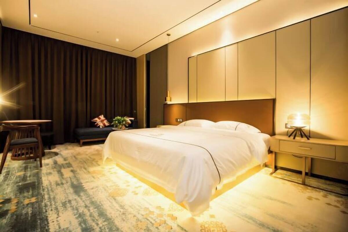 Een moderne hotelkamer met een groot bed, een bureau en een nachtkastje met een lamp.