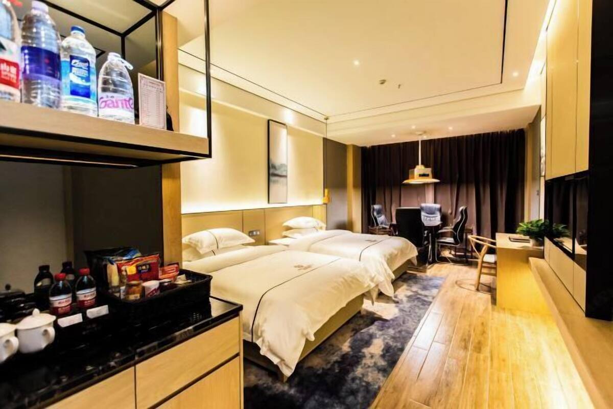 Een moderne hotelkamer met twee bedden, een bureau, een stoel, een televisie en een minibar.