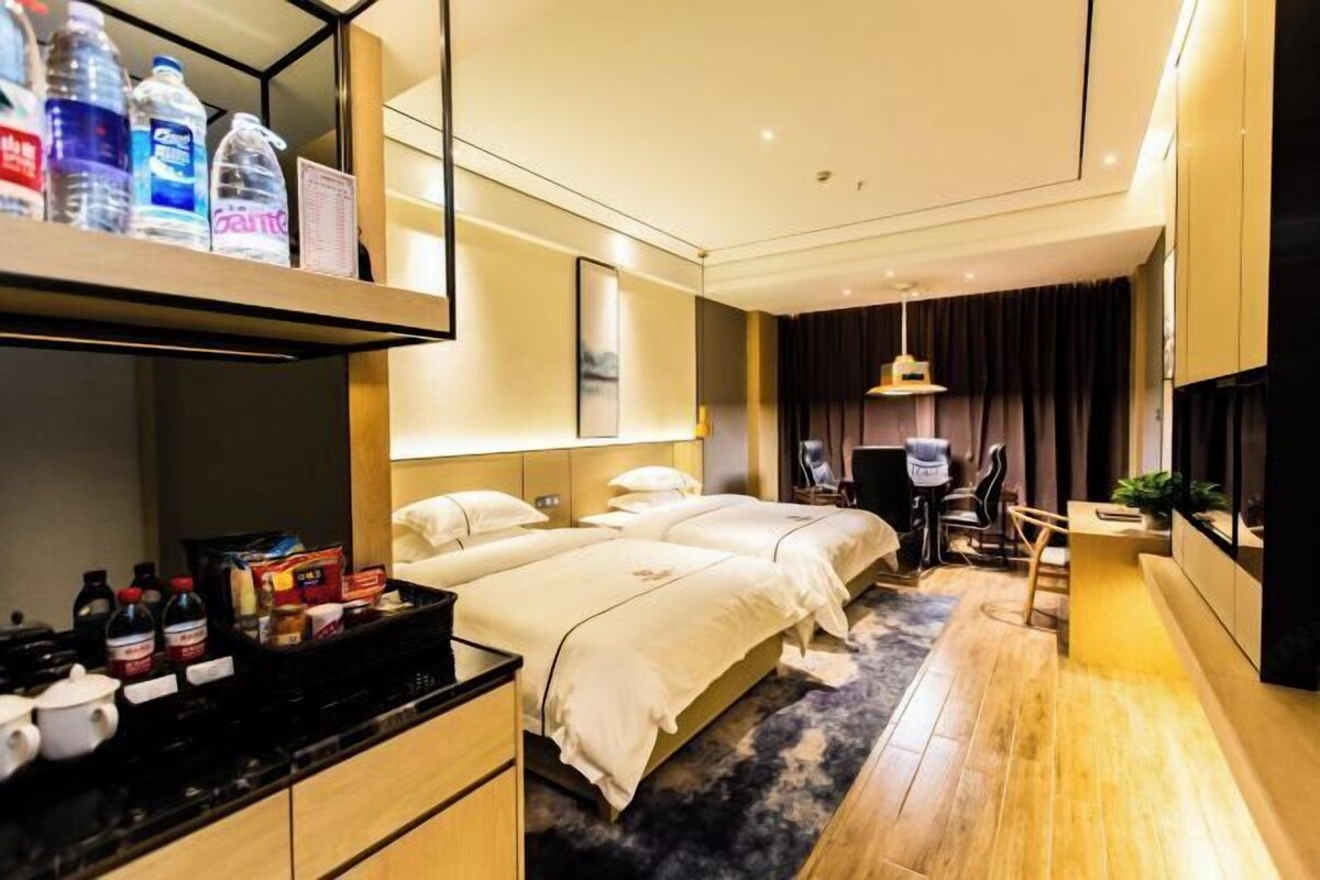 Una habitación de hotel con dos camas, un escritorio, una silla, un televisor y un mini bar.