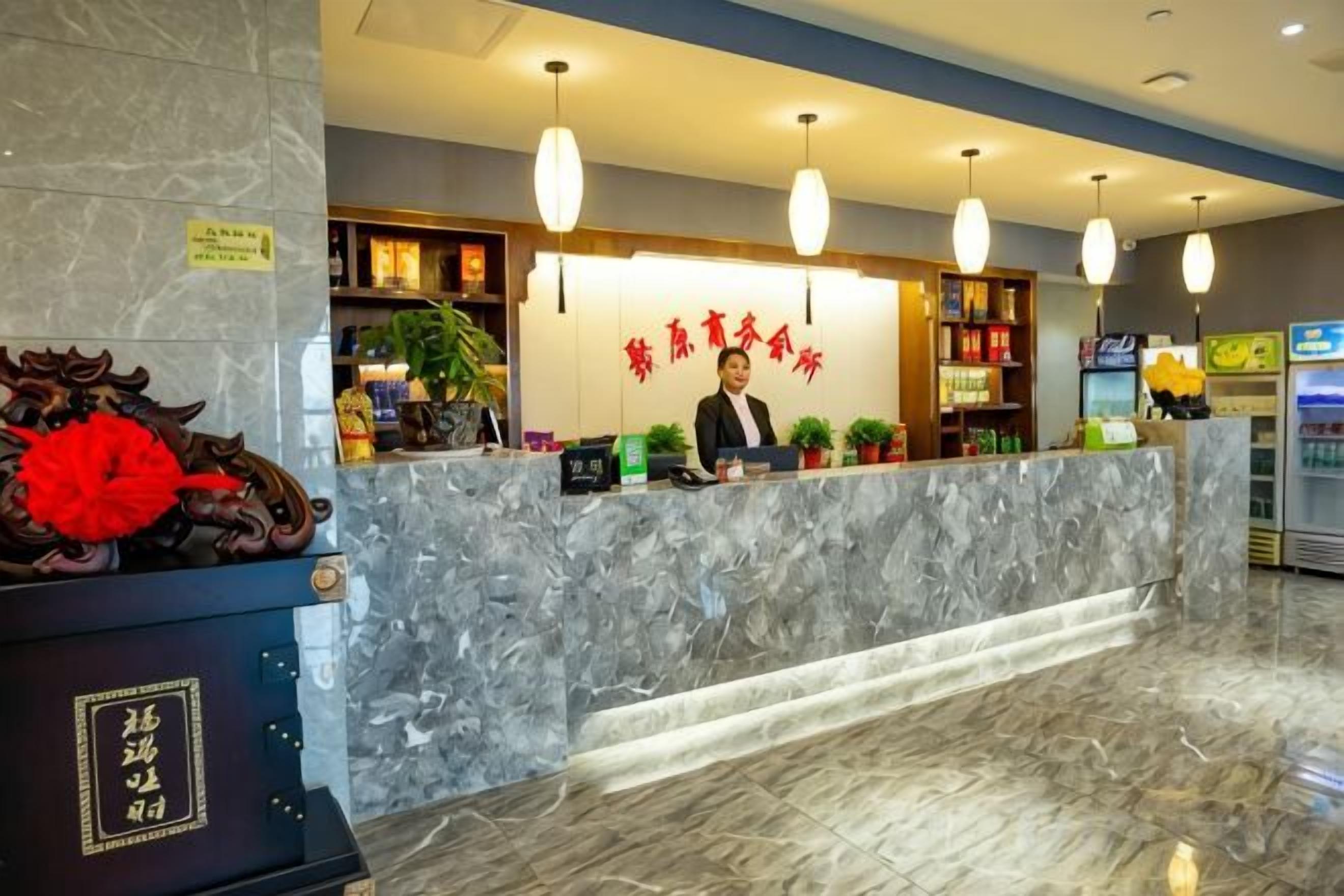 A hotel reception area with a marble counter, a receptionist, and a vending machine.