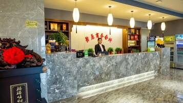 A hotel reception area with a marble counter, a receptionist, and a vending machine.