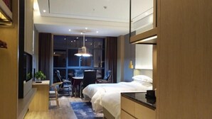 A modern hotel room with a bed, desk, chair, and a TV. - Huarong Mingwei International Hotel (Huarong)