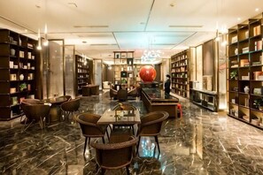A library with bookshelves, a large red spherical sculpture, and a marble floor. - Huarong Mingwei International Hotel (Huarong)