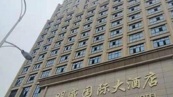 A tall building with multiple windows and a sign indicating it is an international hotel.