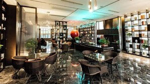 A modern lobby with a glass partition, a central round table, and wicker chairs. - Huarong Mingwei International Hotel (Huarong)