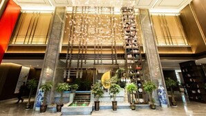 A modern lobby with a central staircase, potted plants, and a decorative ceiling feature. - Huarong Mingwei International Hotel (Huarong)