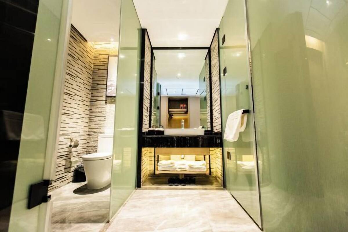 Een moderne badkamer met een douchecabine van glas, een marmeren vloer en een toilet.