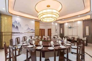 A dining area with round tables, chairs, and a chandelier.