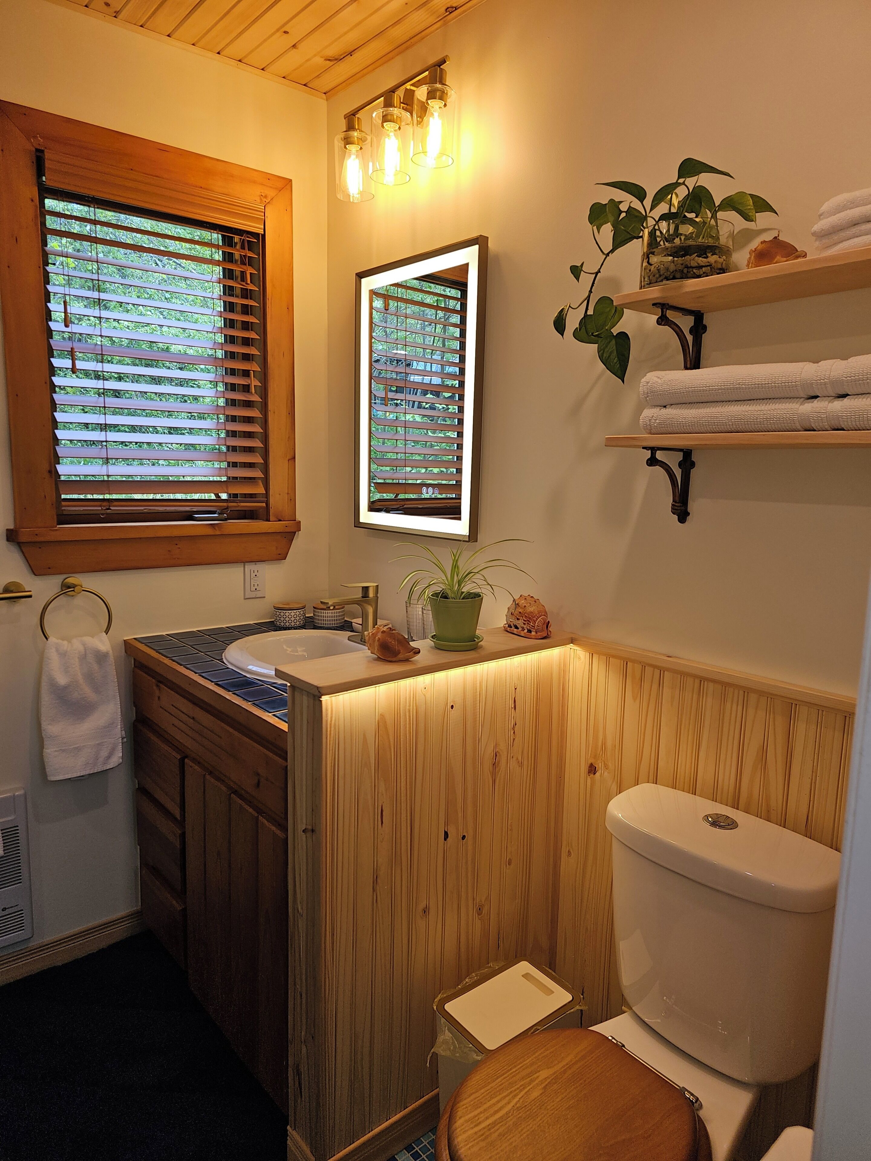 Et badeværelse med en trævognbane, toilet, håndvask og et vindue med skodder.