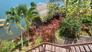 A wooden staircase leading to a deck overlooking a body of water, surrounded by lush tropical vegetation.