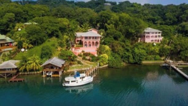 A tropical resort with overwater bungalows, a central building, and a dock with a boat.