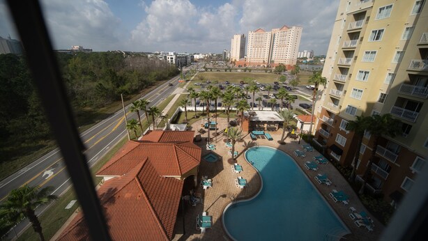 Un hotel con piscina, varios pisos y vistas del entorno, incluyendo calles y otros edificios.