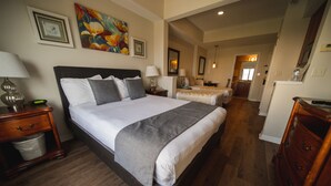 Un dormitorio amplio con una cama grande, mesitas de noche y un buró. Se ve un baño al fondo.