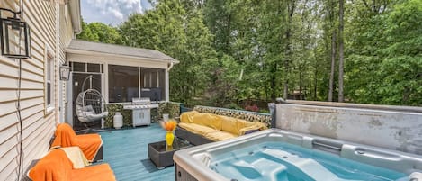 Patio trasero con jacuzzi, mobiliario exterior y una zona cubierta con parrilla.