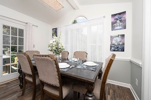 A dining room with a wooden table set for four, surrounded by upholstered chairs.