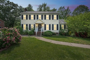 A two-story house with a front porch, a driveway, and a well-maintained lawn.