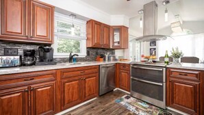 A modern kitchen with wooden cabinets, stainless steel appliances, and a large window.