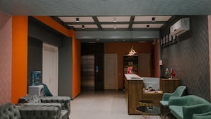 A modern hotel lobby with a reception desk, seating area, and a kitchen in the background. - Hotel Madinah (Baku)
