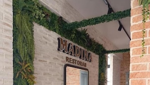 A restaurant named 'Madina Restoran' with a brick wall and green plants. - Hotel Madinah (Baku)