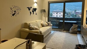 Een moderne woonkamer met een bank, een salontafel en een laptop. Op de muur hangt een wereldkaart en een decoratie met kattenmotieven.