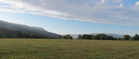 A vast open field with distant hills and a partly cloudy sky.