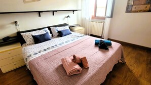 A bedroom with a bed, a bedside table, a nightstand, a radiator, and a window with curtains. - FLORENCE HOMEAWAY - COZY APARTMENT NEAR FLORENCE AIRPORT -18 min from City center (Firenze)