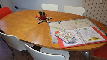 Ett runt träbord med en karta, en röd pärm och en kaktus i en röd mugg.