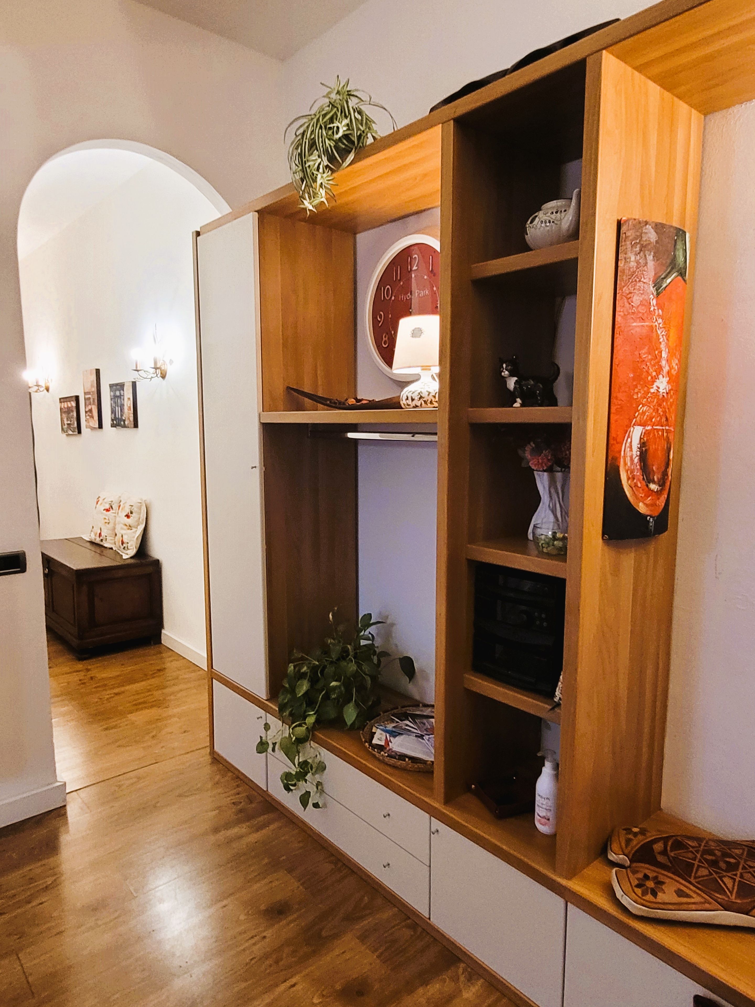 A room with a wooden cabinet, a clock, and a plant.