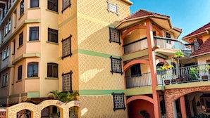 Un edificio de varios pisos con balcones, una entrada de ladrillo y plantas en macetas.