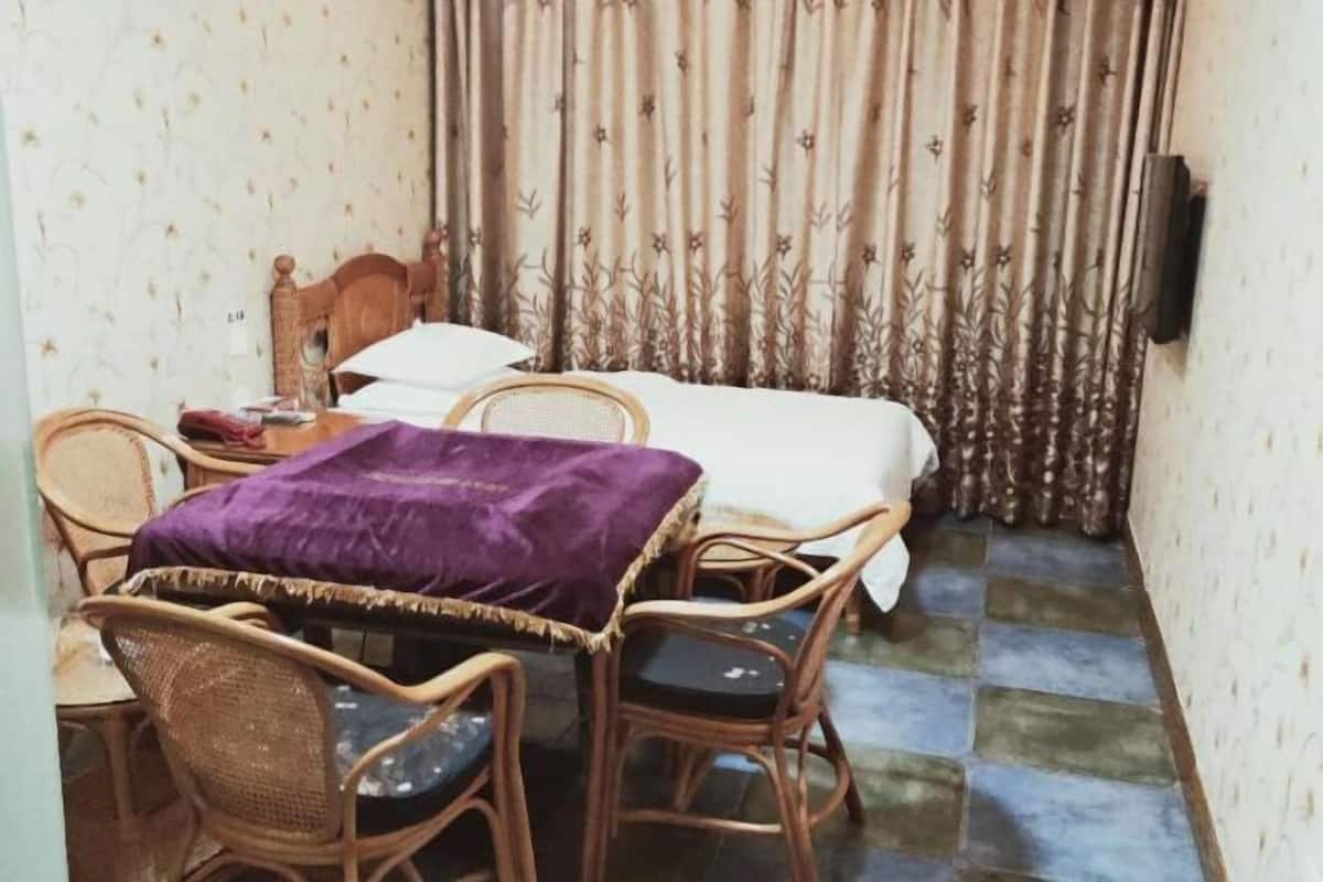A small room with a bed, a table with chairs, and a purple blanket on the table.
